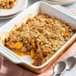 Homemade peach crisp in a baking dish with golden oat topping – peach recipes dessert