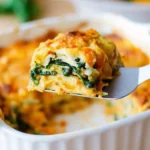 a slice of butternut squash and spinach lasagna lifted out of a white casserole dish