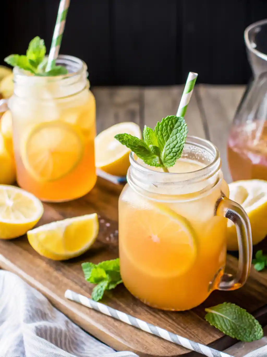 Homemade iced peach green tea served in mason jars with lemon slices, ice, and fresh mint, perfect for refreshing summer recipe ideas.