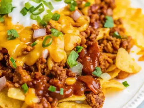 Delicious Frito Chili Pie topped with cheese and served in a skillet.