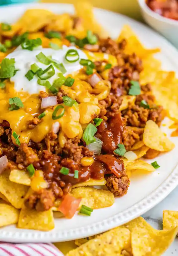 Delicious Frito Chili Pie topped with cheese and served in a skillet.
