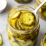 Bread and Butter Pickles being picked up from a Jar Using a Fork