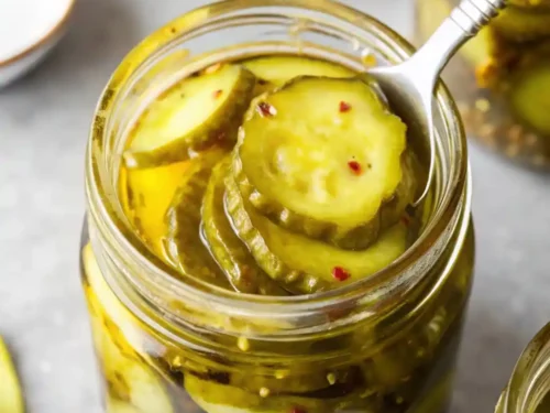 Bread and Butter Pickles being picked up from a Jar Using a Fork