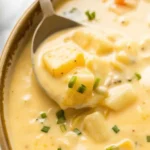 Bowl of creamy cheesy potato soup topped with crispy bacon and green onions