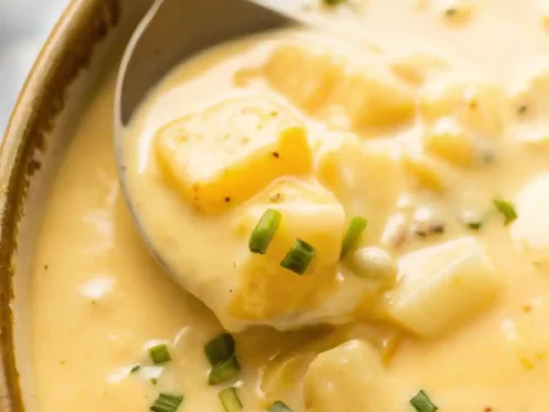 Bowl of creamy cheesy potato soup topped with crispy bacon and green onions