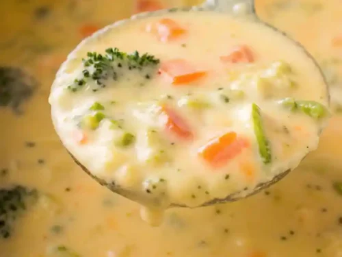 Bowl of creamy broccoli cheddar potato soup with broccoli florets and sharp cheddar cheese.