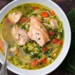 Salmon fish soup recipe in a bowl. A side of bread