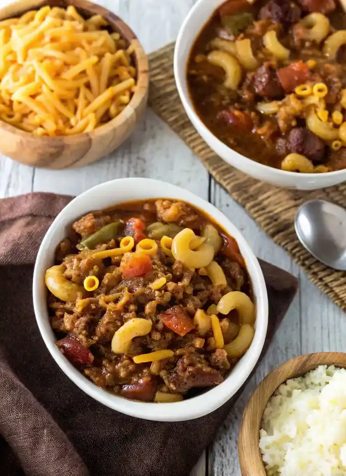 Delicious bowl of chili and noodles, garnished with fresh herbs and spices.