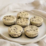 Individual baked Oreo cheesecakes with cookie bases on a platter.